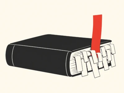 Closed black notebook with many white tabs sticking out from the spine and a red bookmark flag beside it.