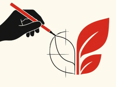 Black hand holding a red pencil drawing a circular blueprint beside a red plant leaf on a pale background.