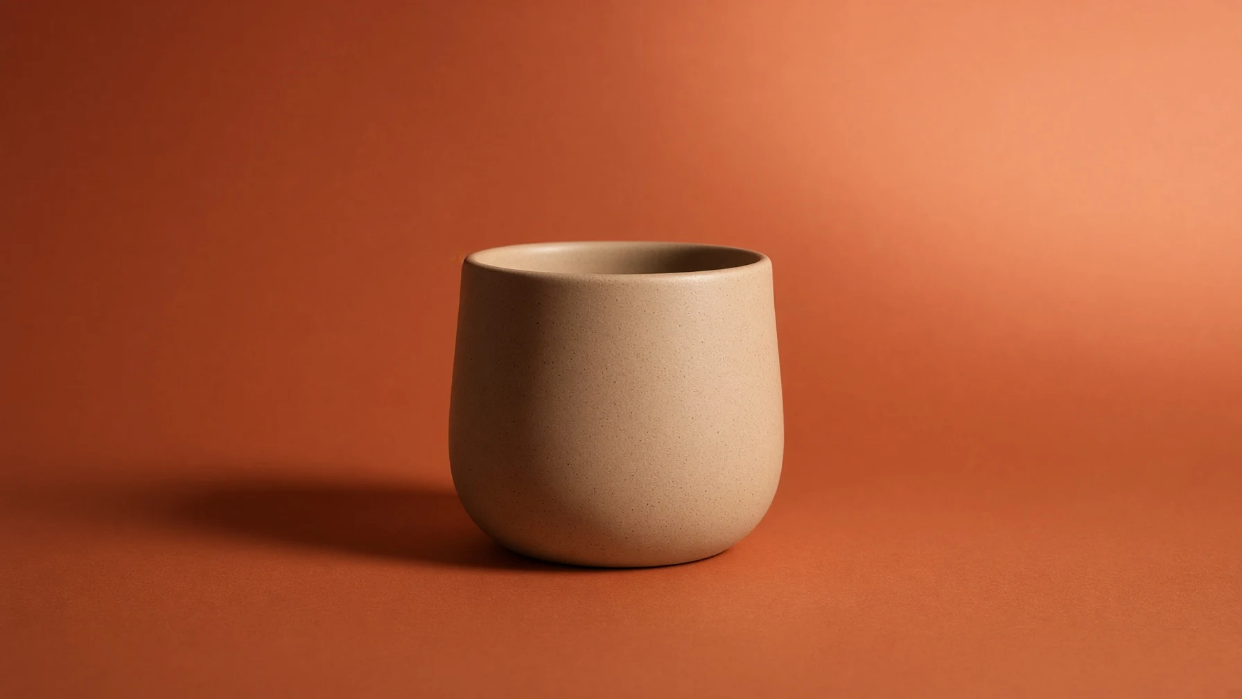 Minimalistyczne zdjęcie produktowe ceramicznego kubka na terakotowym tle