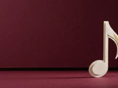 Wooden cutout of an eighth note standing on a burgundy surface and backdrop.