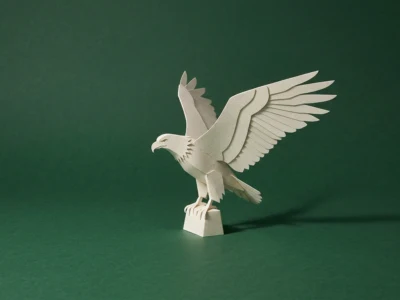 Paper sculpture of an eagle with wings spread, crafted from white cardstock, standing on a small pedestal against a green background.