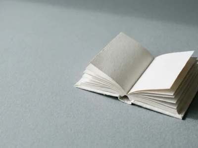 Small blank open notebook with white pages on a gray surface, pages fanned out gently.