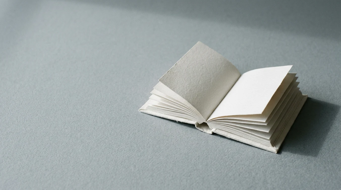 Funkcja informatywna po czym ją poznać przykłady i pułapka tekstów które ją udają - Promptowy Small blank open notebook with white pages on a gray surface, pages fanned out gently.