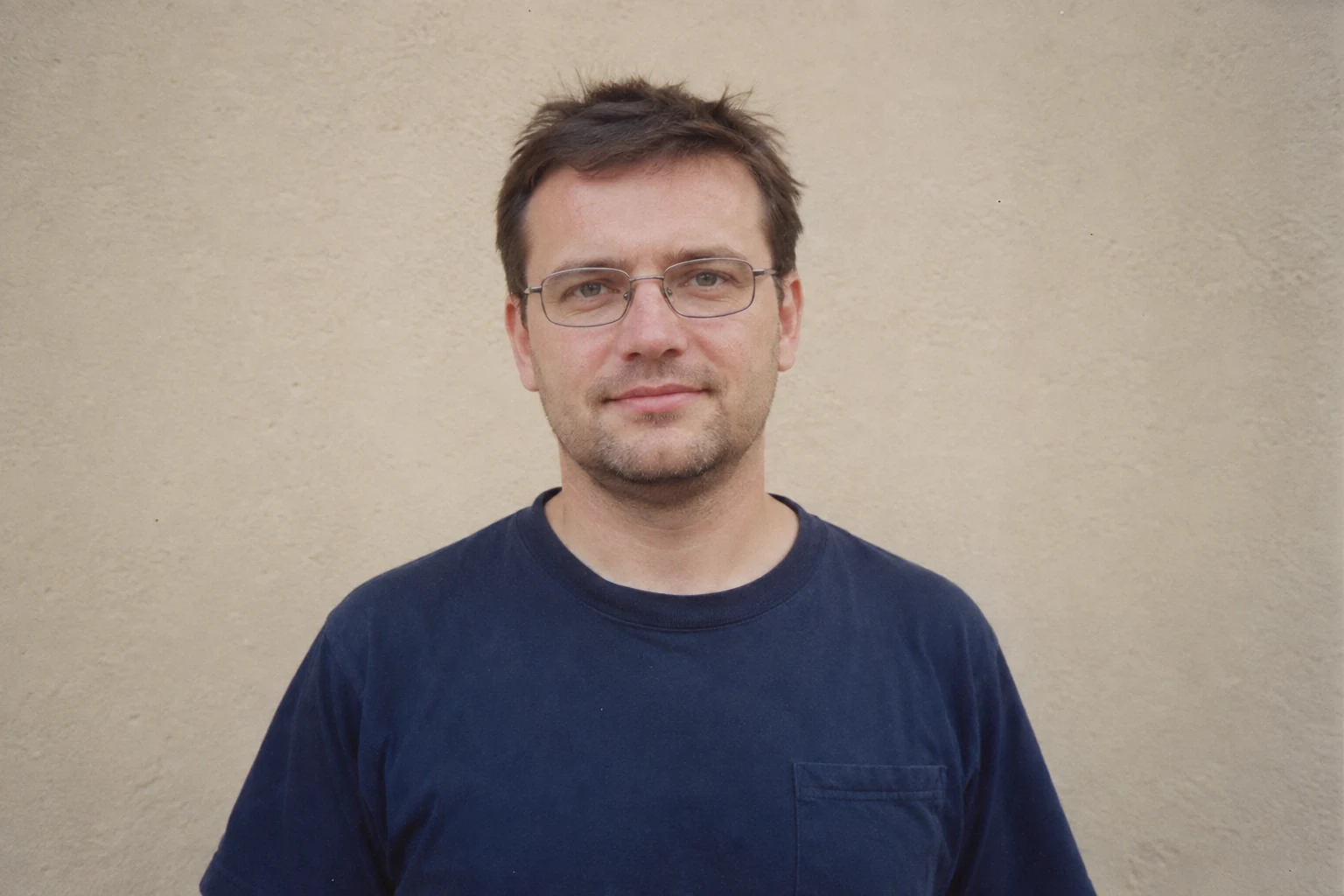 Mężczyzna w okularach na jednolitym beżowym tle z całą głową widoczną w kadrze - Promptowy Mężczyzna w okularach na jednolitym beżowym tle, z całą głową widoczną w kadrze
