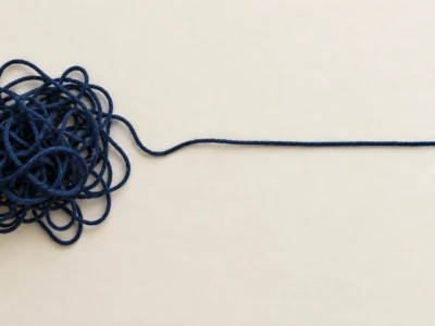 Splątana granatowa nić przechodząca w prostą linię. - Promptowy Blue tangled ball of string with a single long strand extending to the right on a light background.