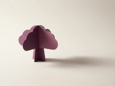 Purple paper tree sculpture with scalloped cloud-like leaves on a pale surface