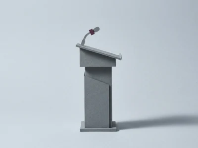 Gray podium with a curved microphone on a stand against a pale background, ready for a speech.','Note: fix quotes