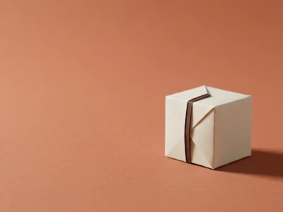 Small white gift box tied with a brown ribbon on a peach background.