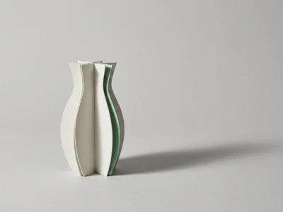 Usuwanie tła w AI jak zrobić to dobrze przy włosach szkle i cieniu - Promptowy Minimalist paper sculpture formed by layered curved sheets in white and pale green on a gray surface with a soft shadow to the right.