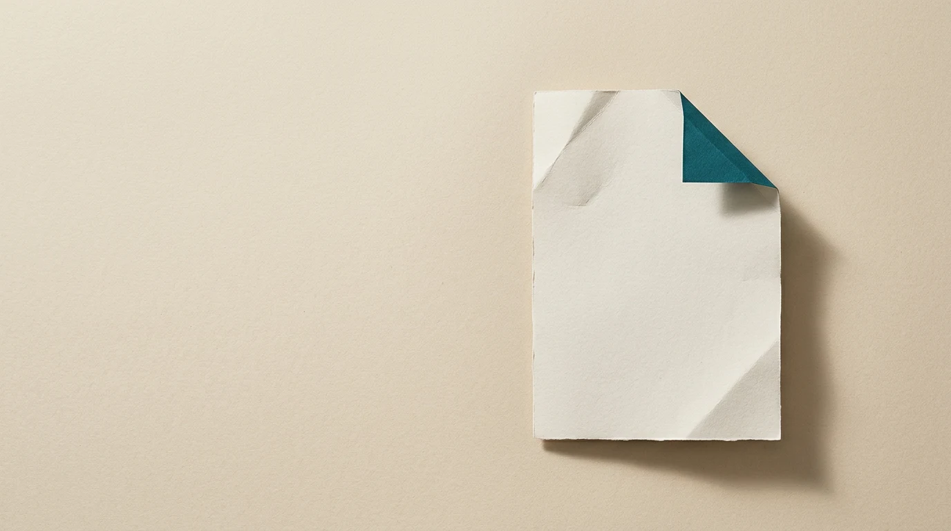 White square sheet of paper with a teal folded corner on a beige background.