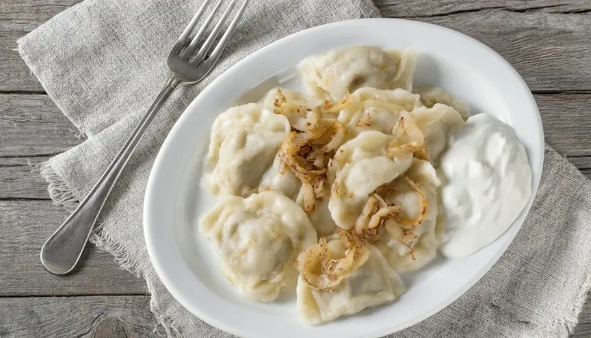 Qwen-Image 2.1: pierogi z przysmażaną cebulką i śmietaną na białym talerzu